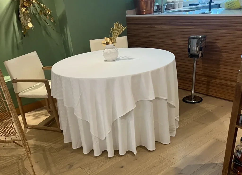 Mantelería blanca redonda hasta el suelo con cubres cuadrados de lino instalada por Currás y Salgado en el Restaurante Gunnen de Matogrande, A Coruña.