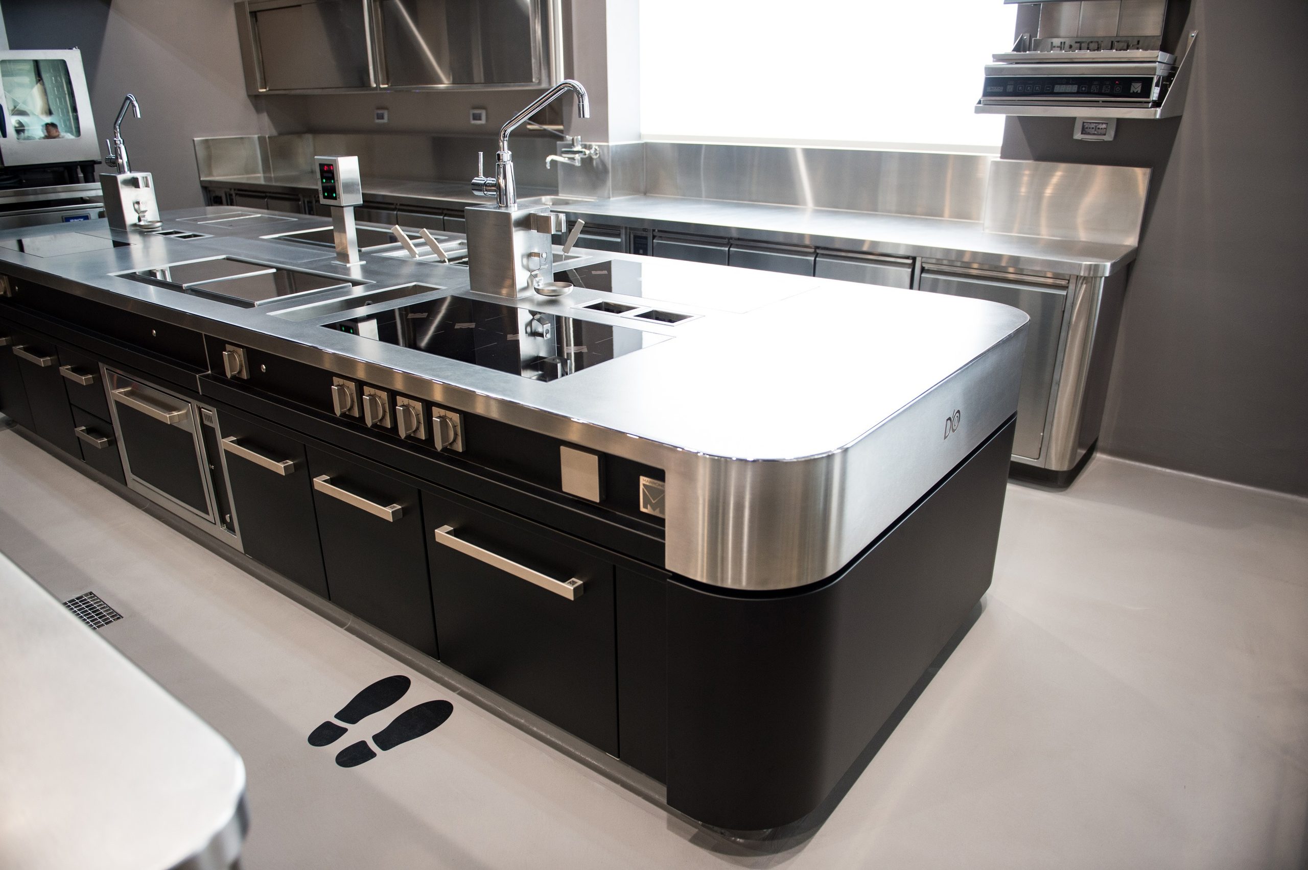 Cocina profesional con isla central negra y acero inoxidable